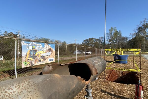 photo of a damaged pipe in front of a sign that says call 811 before you dig