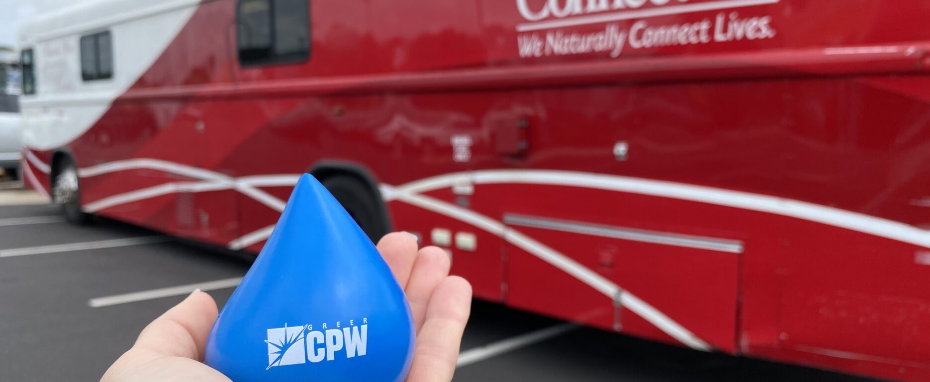 Photo of stress ball shaped as a blood droplet in front of The Blood Connection bus.
