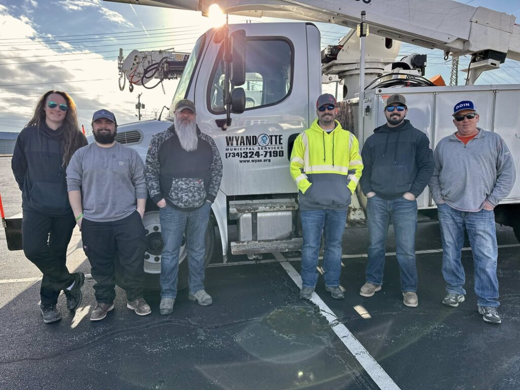 6 linemen pose next to a utility truck.