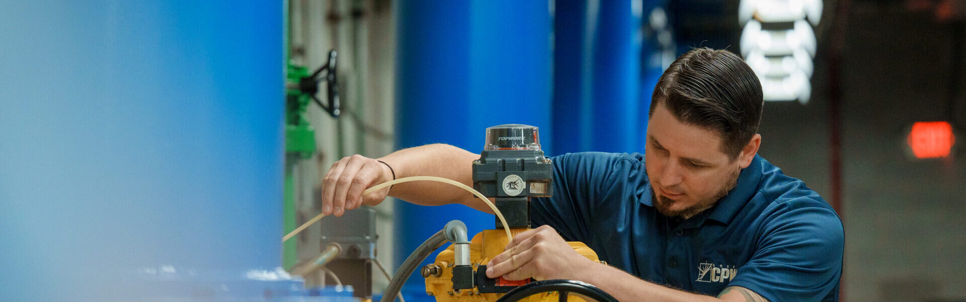 image of a water treatment plant employee inspecting equipment