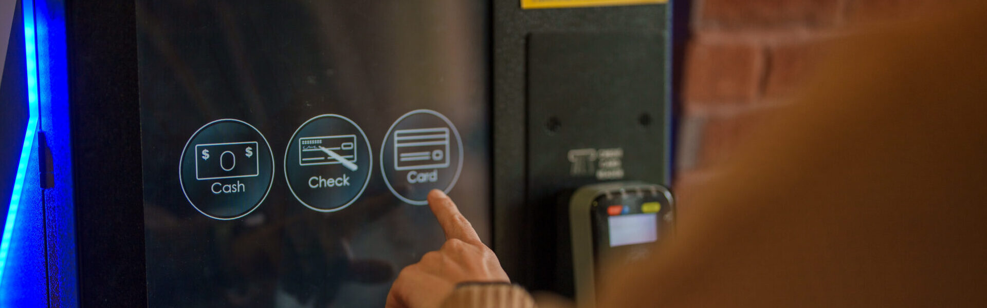 image of a hand and finger being used on the touch screen kiosks to make a payment