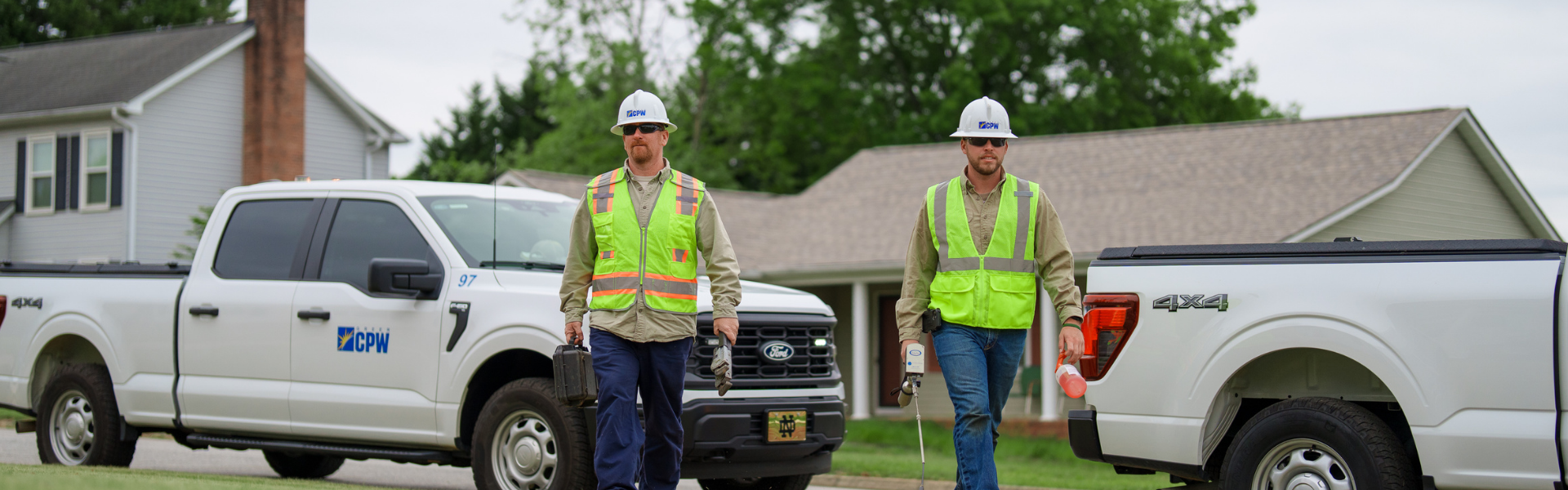 two natural gas employees carrying tools while walking_1920_600